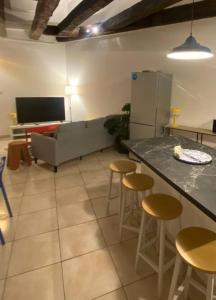a living room with a couch and bar with stools at Grands appartements dans la vieille ville in Périgueux