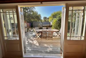 an open door to a deck with a table and chairs at The Happy Place, private cottage with rustic pool in Van Wyksdorp