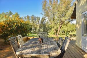 a wooden table with chairs on a deck at The Happy Place, private cottage with rustic pool in Van Wyksdorp
