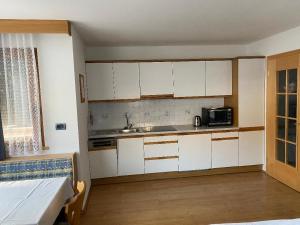 a small kitchen with white cabinets and a microwave at Apartments Nadia in San Vigilio Di Marebbe