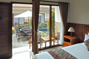 a bedroom with a bed and a balcony with a patio at Cening Ayu Sanur in Sanur