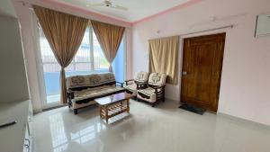 a living room with chairs and a table and a door at Yashwithaa Homestay Tirupati - New Hill View Apartments with Balcony, AC, WiFi, TV in Tirupati