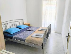 a bedroom with a bed with blue pillows and a window at Gospoja Park & Beach Apartment Vrbnik in Vrbnik