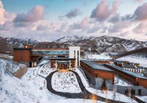 崇礼崇礼奥克伍德优阁酒店公寓的一座被雪覆盖的建筑,背景是群山