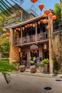 a building with a balcony and orange umbrellas on it at Hội An Spirit Homestay in Hoi An +69 photos