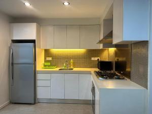 a kitchen with white cabinets and a stainless steel refrigerator at Bukit Bintang KLCC Fairlane suite by Rose in Kuala Lumpur +8 photos