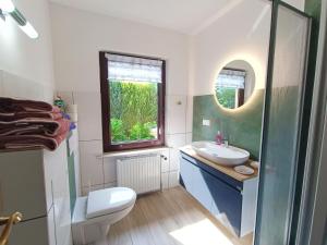ein Badezimmer mit Waschbecken und Toilette und einem Fenster in der Unterkunft Ferienappartements Haus Fischersruh in Lauterbach