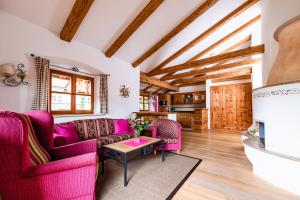 a living room with purple furniture and wooden ceilings at Hotel garni Fischerweber am See in Rottach-Egern