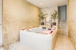 Maison Spa et Sauna, Cœur de la Normandie في Ranville: حوض استحمام في غرفة بجدار من الطوب