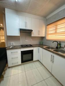 a kitchen with white cabinets and a sink at L & B Homes in Maun