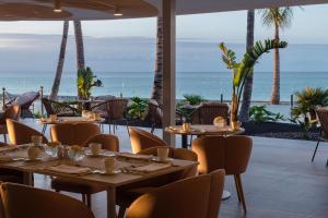 a restaurant with tables and chairs with the ocean in the background at Plus Fariones Suite Hotel in Puerto del Carmen