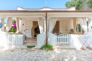 a white house with a white fence and an umbrella at Villa Serenità in San Vito dei Normanni