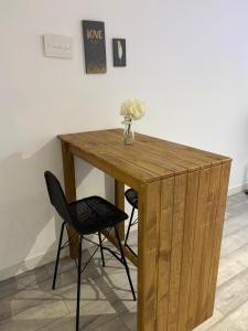 a wooden table with two chairs and a vase of flowers on it at Superbe grand studio, parking in Saint-Priest +6 photos