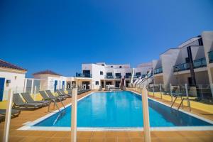 a swimming pool with chairs and a building at TAO El Cotillo - VV in El Cotillo
