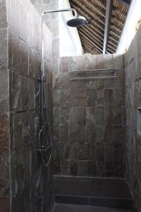 y baño con ducha y pared de piedra. en Villa Bayu, en Temukus