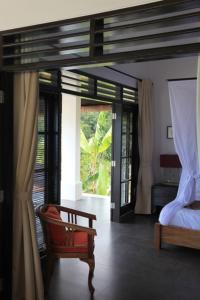Un dormitorio con una cama y una silla y ventanas. en Villa Bayu, en Temukus