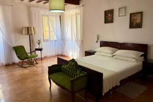 a bedroom with a large bed and a green chair at B&B Antica Dimora in Pergola