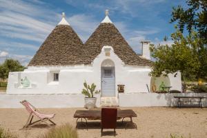 a white house with a roof with a table and chairs at Trullo Elce 11 in Putignano
