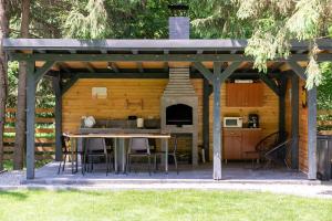 a pergola with a table and a kitchen at Urban Forest House in Porumbacu de Sus