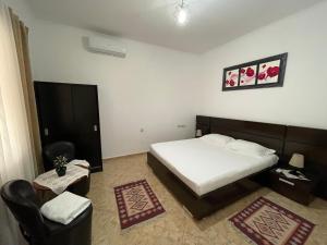 a bedroom with a bed and a chair and a television at Anthony&Amar in Berat