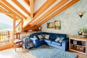 a living room with a blue couch and wooden ceilings at Mansarda sul Lago di Molveno in Molveno