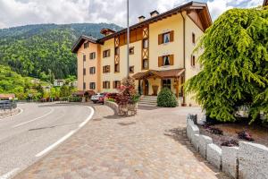a large yellow building on a street next to a road at Mansarda sul Lago di Molveno in Molveno