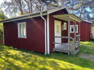 un hangar rouge avec une véranda et un escalier dans l'établissement Kolonin Kuggaviken, à Åsa