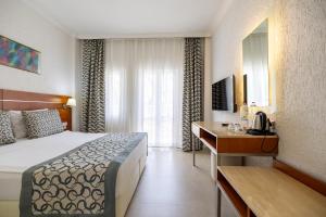 a hotel room with a bed and a desk at Petunya Beach Resort in Ortakent