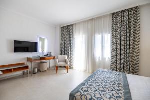a bedroom with a bed and a desk and a television at Petunya Beach Resort in Ortakent