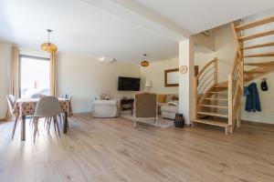 a living room with a table and chairs and a staircase at La Maison du Martrait - Proche de la plage in Graye-sur-Mer