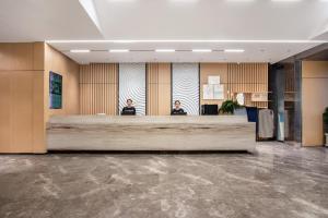 zwei Männer sitzen an einem Rezeptionstresen in einer Lobby in der Unterkunft Atour Hotel Hangzhou Xiaoshan Peoples Square in Hangzhou