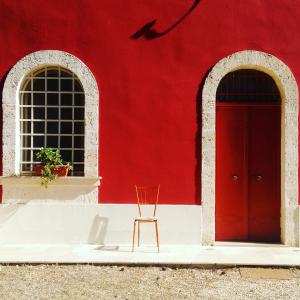 ein rotes Gebäude mit einer roten Tür und einem Stuhl in der Unterkunft Il Boschetto in San Vito dei Normanni