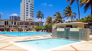 a swimming pool at a resort with palm trees and buildings at Chefs Delight in San Juan