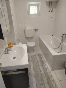 a bathroom with a sink and a tub and a toilet at Breladreams Apartment in Brela