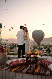 a man and a woman standing on a rooftop with balloons at Cappadocia Cave Suites Adult Only in Goreme