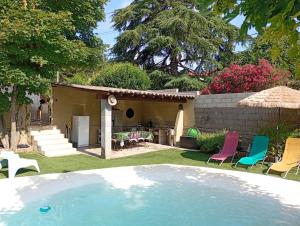 un patio trasero con piscina y sillas y una casa en Maison, en Alès