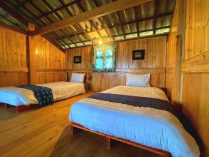 two beds in a room with wooden walls at Rosevine - Homestay Trekking Tour in Sa Pa