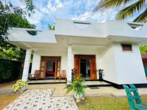 a white house with a porch and chairs at Bentota Upali Villa in Bentota