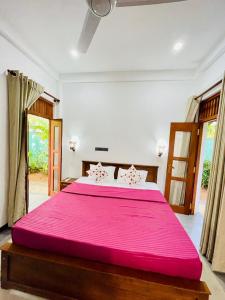 a bedroom with a large bed with a pink blanket at Bentota Upali Villa in Bentota