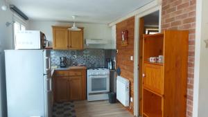 a kitchen with wooden cabinets and a white refrigerator at La petite maison Gîte 2 étoiles in La Bresse +5 photos