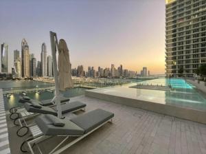 a pool with an umbrella and lounge chairs on a building at Elegant 1BR Apartment with Sea View and Free Beach Access in Dubai