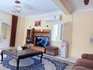 a living room with a table and a tv at Diana Beach Villa spacious detached فيلا واسعه مستقله ديانا ONLY FAMILIES بيتش in Dawwār al Ḩajj Aḩmad