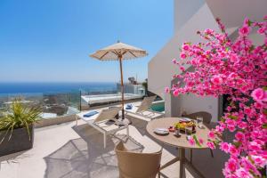 un patio con mesa, sillas y flores rosas en SantoView Suites, en Vourvoúlos