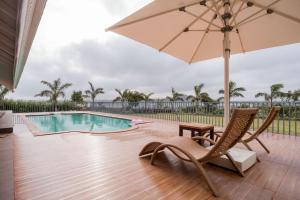 ナーシクにあるStayVista's Eva Villa - Lakeside Luxury with Modern Decor, Pool & Expansive Lawn - Near Sulaのパティオ(パラソル、椅子付)、プールが備わります。