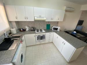 a small kitchen with white cabinets and a sink at Poolside Escape - Polis in Polis Chrysochous