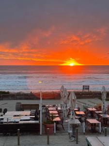 un tramonto in spiaggia con tavoli e sedie di Le Grand Large - T2 vue océan a Mimizan-Plage