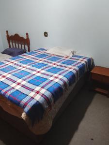 Una cama con una manta azul y blanca encima. en Recanto dos Amigos, en Tietê