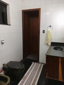 Un baño con un inodoro negro y un lavabo. en Recanto dos Amigos, en Tietê