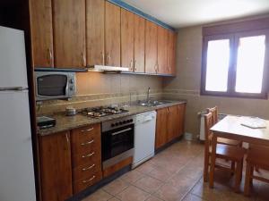 cocina con armarios de madera y horno de fogón blanco en Apartamentos Casa Ferrás, en Valderrobres