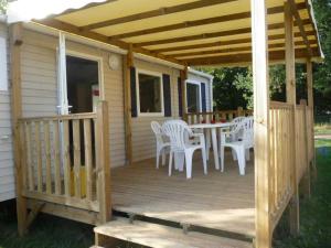 a wooden deck with a table and chairs on it at Camping 4 étoiles - Piscine - eecaad in Aureilhan